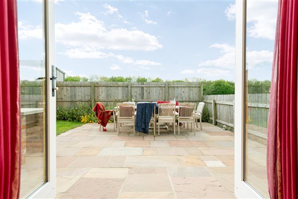 french windows onto the garden with a large patio and table with chairs